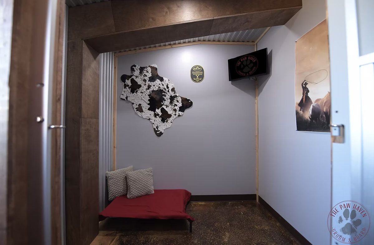The Montana Grand Suite — private themed room with a red dog bed, pillows, cowhide wall décor, and a TV