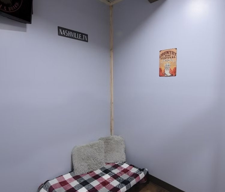 The Tennessee Luxury Suite — private Nashville-themed room with a plaid bed, plush pillows, and a TV