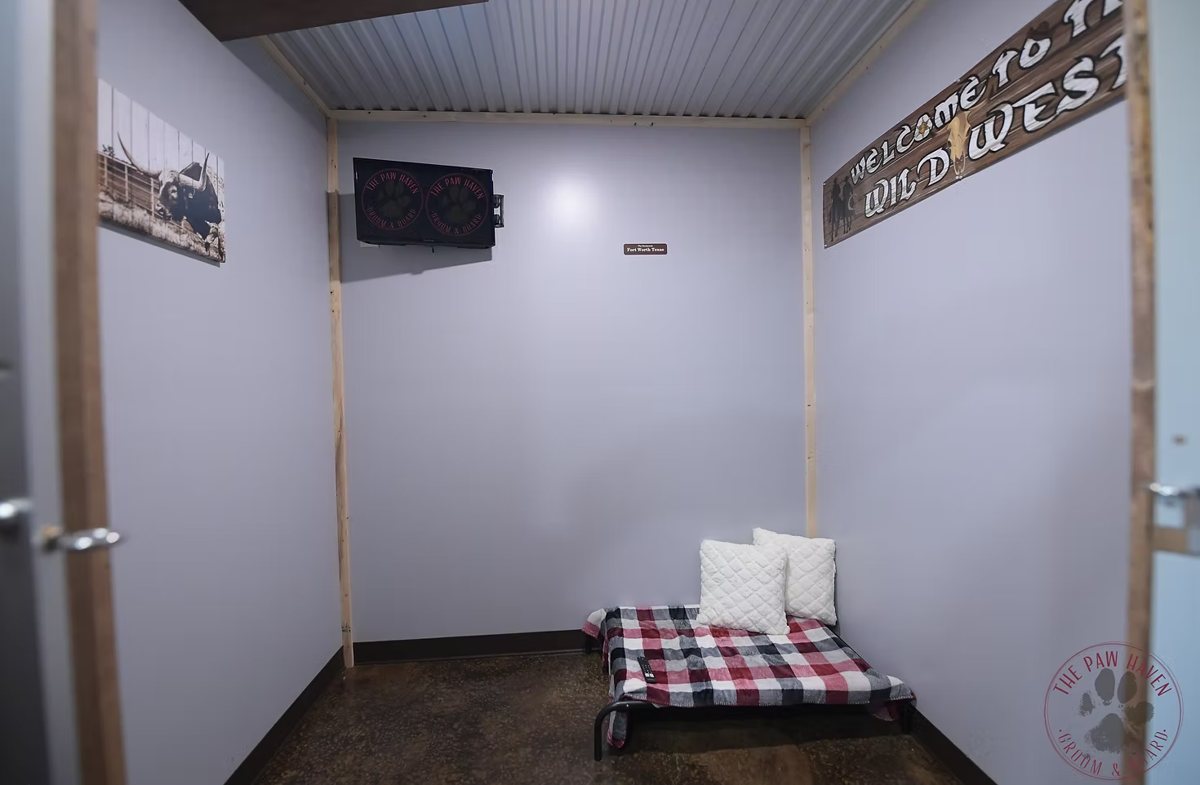 The Texas Grand Suite — private Wild West themed room with a raised bed, plaid blanket, pillows, and a TV